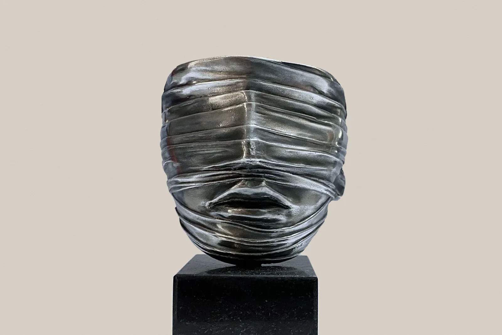 Igor Mitoraj, „Twarz zawoalowana”, 1977 – srebrzysta rzeźba twarzy spowitej pasmami, na czarnej podstawie